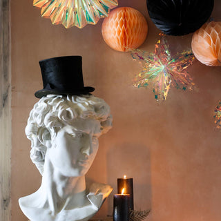 image of honeycomb Christmas decorations and iridescent fans above a bust statue wearing a top hat.