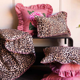Leopard print throw and cushions styled on a black bench with pink cushions too.