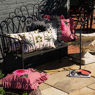 A black garden bench with 4 outdoor cushions styled on it.