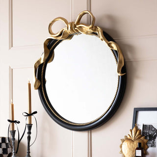 A round gold mirror with milagro heart design.