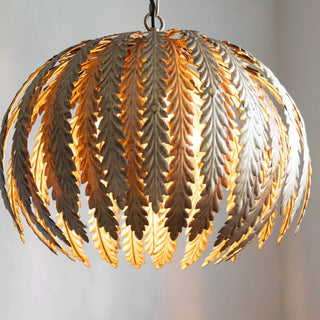 Beautiful gold fern ceiling light suspended from ceiling. The ceiling light is lit.