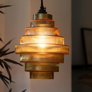 A tiered amber glass ceiling light styled with a plant in the background.
