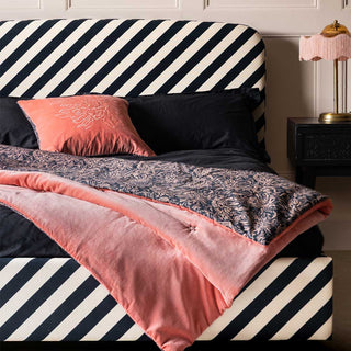Stripe Bed decorated with pink bedding, cushions and throws.