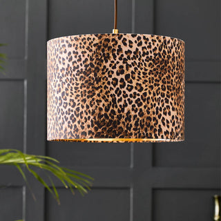 Lifestyle image of the Leopard Light Shade displayed on front of a black panelled wall with a plant.