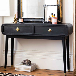 A rattan console table styled with various accessories and a plant.