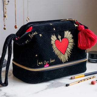 The Chin Up Tits Out Reed Diffuser displayed on a table with some books and a candle.