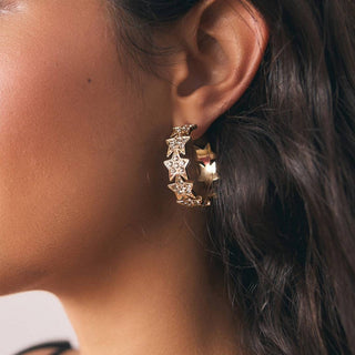 A gold charm bracelet worn by a model.