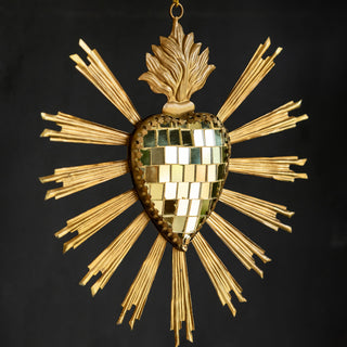 The Gold Disco Ball Heart Hanging Ornament displayed in front of a black wall.