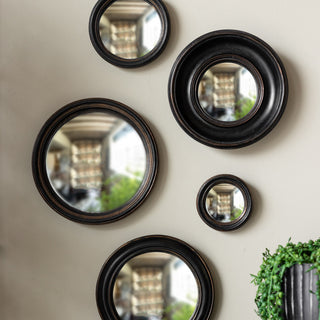 Image of various black Rockett St George wall mirrors displayed on a white wall, styled with a plant in a black plant pot. 