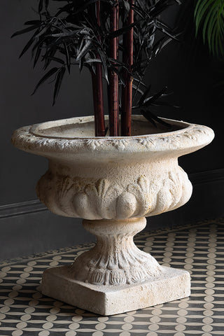 The Classical Stone-Effect Planter styled on a geometric floor with a plant inside.