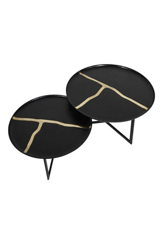 A 'cut out' image of a next of two iron tables, each with gold inlay, against a white background