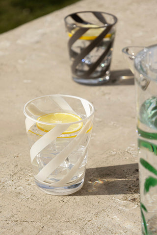 The spiral water glass tumbler on a concrete outdoor table. In the background is a black spiral water glass tumbler.
