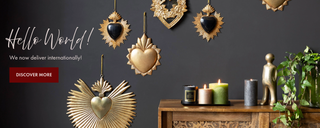 Hello world! We now deliver internationally text on an image of decorative gold hearts.