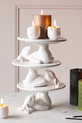 lifestyle image of multiple lazy rabbit cupcake plate on top of each other on a light background with candles on top