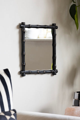 The Black Bamboo Effect Framed wall Mirror displayed on the wall, styled with a plant, sofa and various accessories.