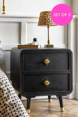 Black nightstand with gold star handles in a bedroom setting, featuring a pink 'Set of 2' label.