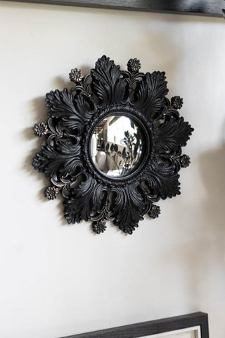 Lifestyle image of small black flowers leaves convex decorative mirror.