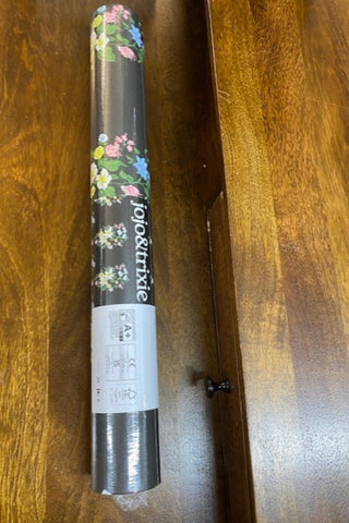 Image of an unopened roll of the JoJo & Trixie Floral New York Black Wallpaper