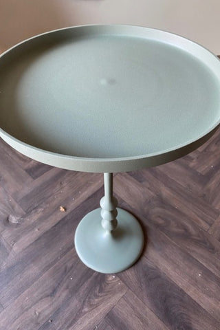 Image of the Anjou Metal Side Table - Sage Green on a wooden floor.