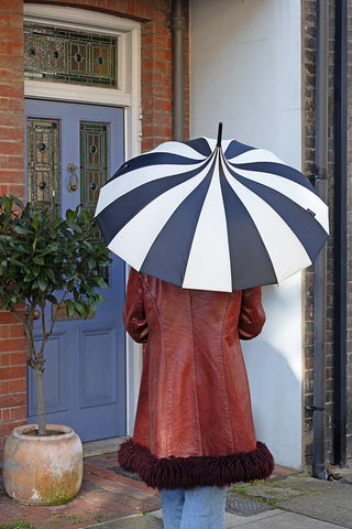 Lifestyle image of the Statement Black & Off-White Umbrella being held outside a town house