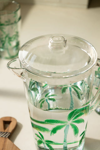 A close up image of the top of a clear acrylic jug with green palm trees on it.