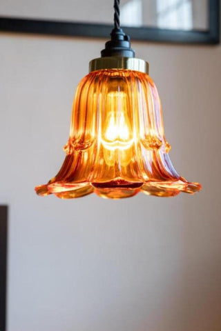 The Amber Vintage-Style Glass Easyfit Ceiling Light Shade attached to a light fitting with the bulb inside illuminated.