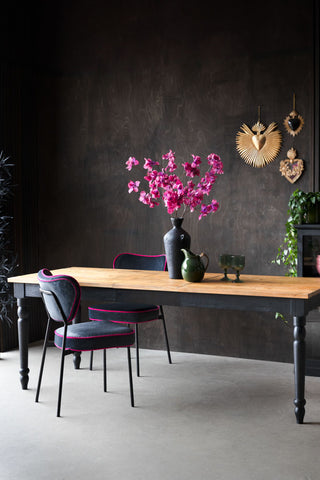 A styled image of the Apothecary Extendable Dining Table with pink flowers and green glassware on it.
