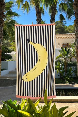 The Banana Beach Towel hanging in the sunshine surrounded by trees and plants.