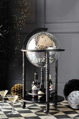 Image of the black and silver disco trolley in a dark room. Around the base of the trolley are cocktails , honeycomb balls and martini glasses.