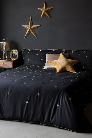 Lifestyle image of the Black Falling Star Duvet Cover and Pillow Case Set displayed on a bed and styled with various home accessories.
