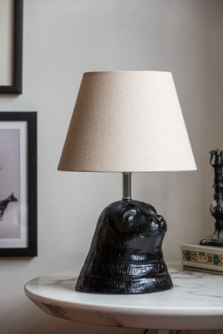 The Black Seal Table Lamp With Linen Shade displayed on a white marble table.