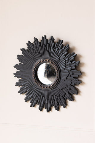 The Black Starburst Traditional Convex round Mirror on a neutral wall.