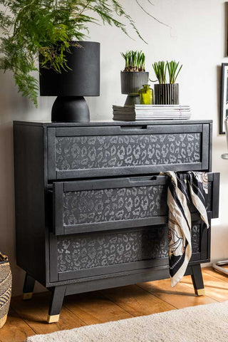 A styled image of the Black Leopard Print Chest Of Drawers with some of its drawers open.