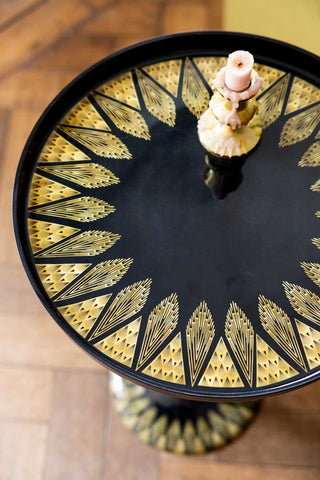 Decorative side table with gold leaf pattern on a wooden floor