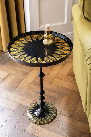 Decorative side table with gold leaf design on a wooden floor