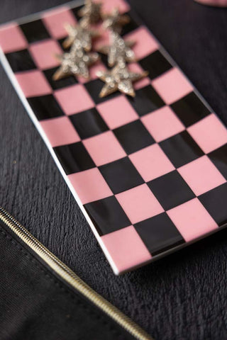 Close-up image of Black & Pink Checkerboard Trinket Dish with star earrings on, styled on a black table.