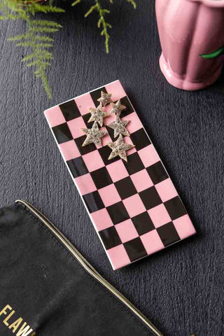 Lifestyle image of Black & Pink Checkerboard Trinket Dish styled on a black table with jewellery and surrounded by home accessories. 
