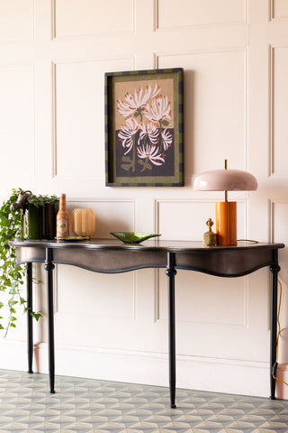 The Black & Gold Antiqued-Style Console Table styled with a lamp, plant and various accessories.