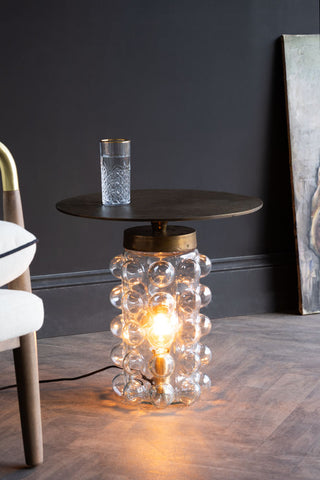 The Bubble Glass Side Table & Floor Lamp for the living room indoor lighting styled with a glass of water on it.