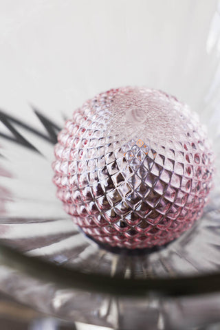 The pink glass bulb of the cocktail table lamp.