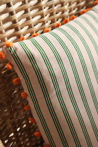 Close-up image of the Cotton Green Stripe Cushion with Orange Pom-Poms