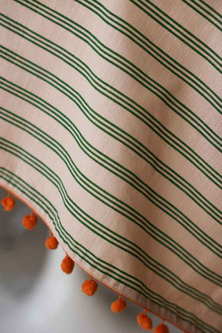 Close-up image of the Cotton Green Stripe Table Cloth with Orange Pom-Poms