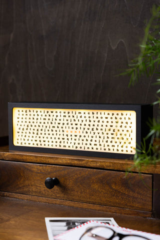 The Cunt Light Box switched on and displayed on a wooden desk.