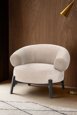 A styled image of the Beautiful Curved Cream Accent Armchair against a wooden wall.