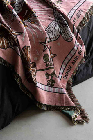 dark pink throw with frill edges hanging on the end of a bed.