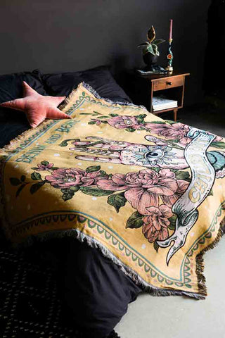 Lifestyle image of the Denim & Bone Yellow Chilled Out Throw on bed against dark wall