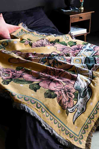 Lifestyle image of the Denim & Bone Yellow Chilled Out Throw on bed against dark wall detail