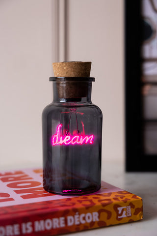 The Dream Neon Bottle Light displayed on a book.