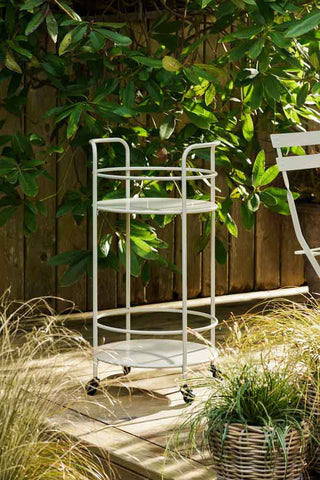The Effortless Outdoor Drinks Trolley in Clay on a decking with plants.