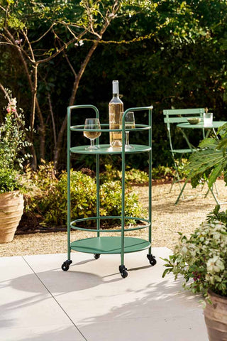 The Effortless Outdoor Drinks Trolley in Slate Green styled with a wine bottle and some wine glasses on, on an outdoor patio.